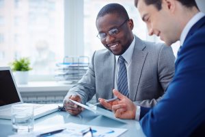 Image of two young businessmen interacting at meeting in office